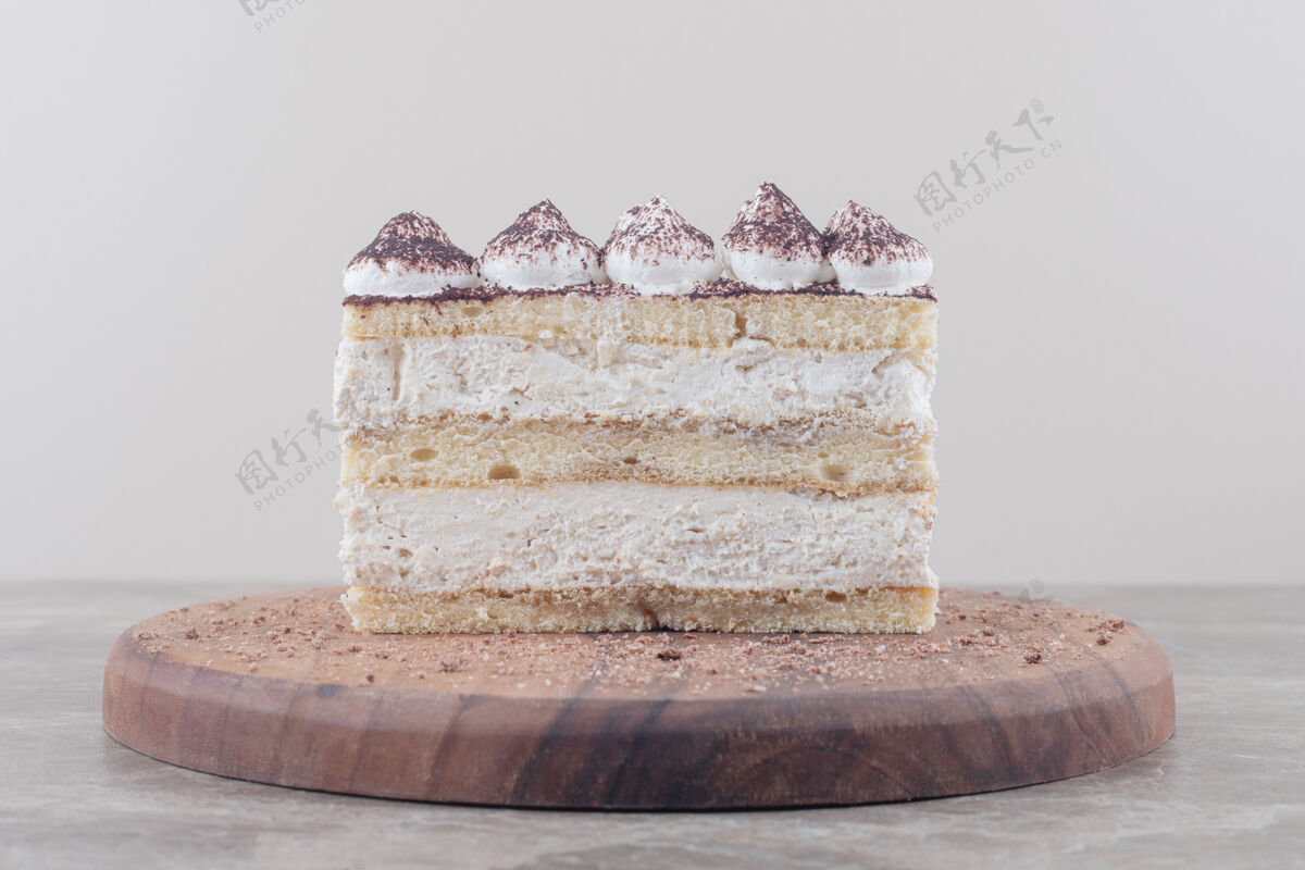 奶油奶油和可可粉覆盖在大理石板上的蛋糕片上美味美味甜点