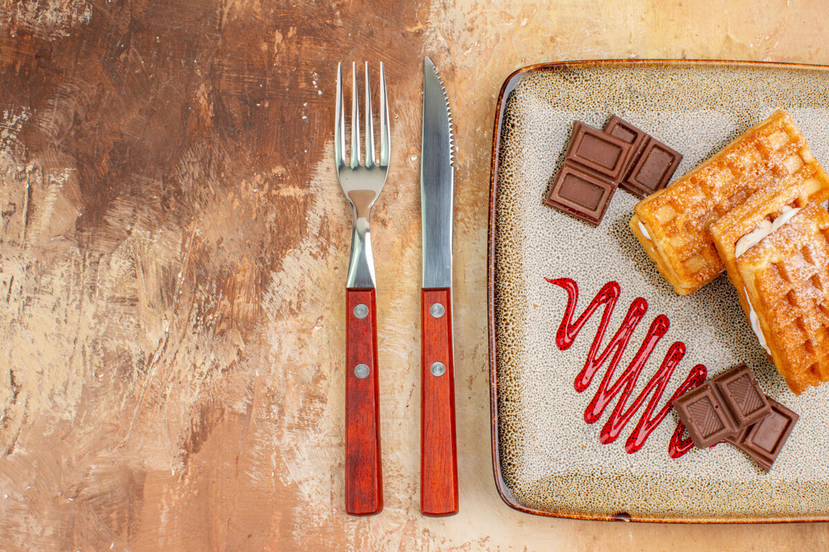 饼干俯瞰美味的华夫饼与巧克力条棕色背景巧克力抹刀背景