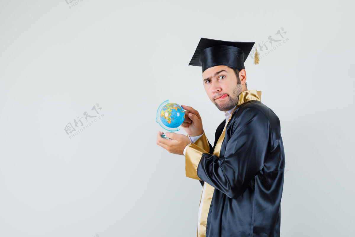 聪明一个穿着毕业制服的年轻人 在学校的地球仪上选择目的地 看上去犹豫不决模特男人立场