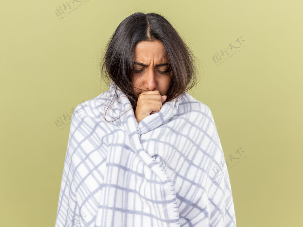嘴咳嗽的年轻病女孩裹在格子布把手放在嘴上橄榄绿的背景隔离疾病年轻格子