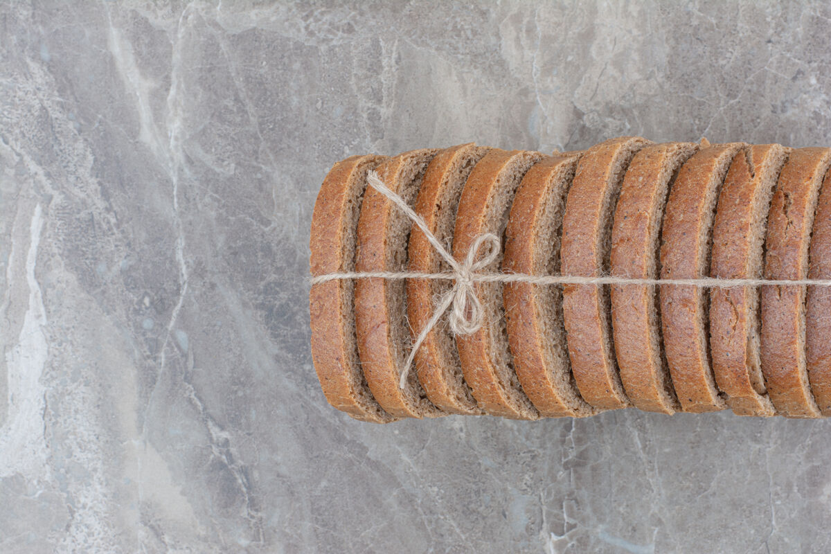 健康用绳子把棕色面包片放在大理石表面面包整个谷物