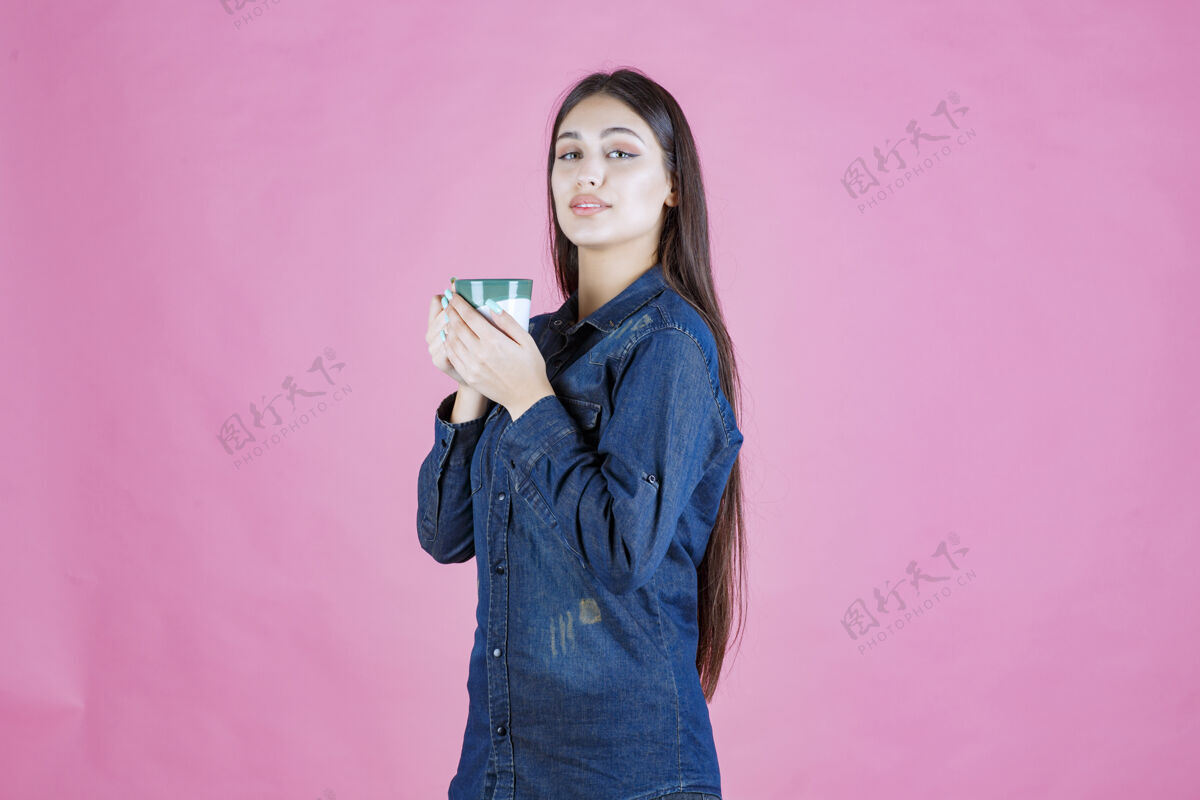 热年轻女子拿着一个白绿色的咖啡杯 闻着女人年轻美食