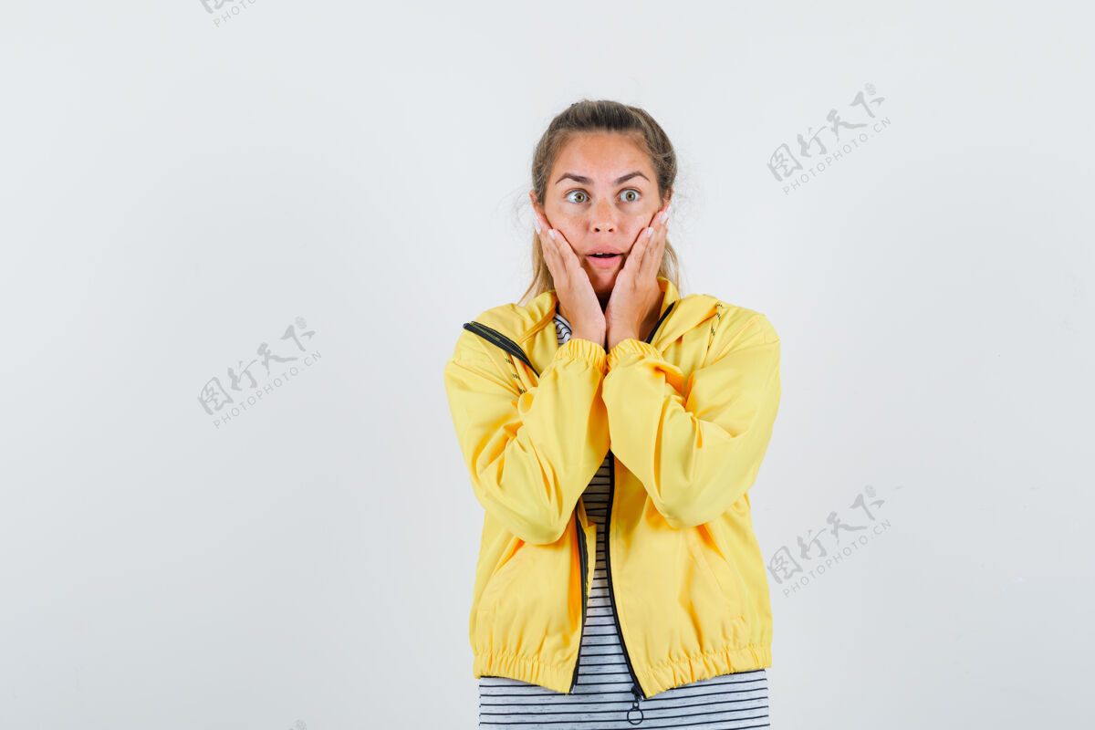 手一个金发女人手把手放在脸上 穿着黄色棒球服和条纹衬衫 看起来很惊讶前面头发年轻