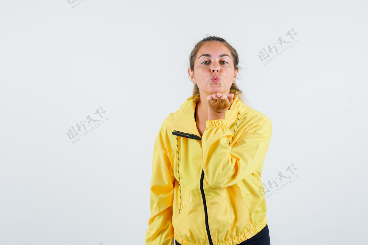女性一个穿着黄色雨衣的年轻女子在空中飞吻 看起来很可爱发送脸肖像