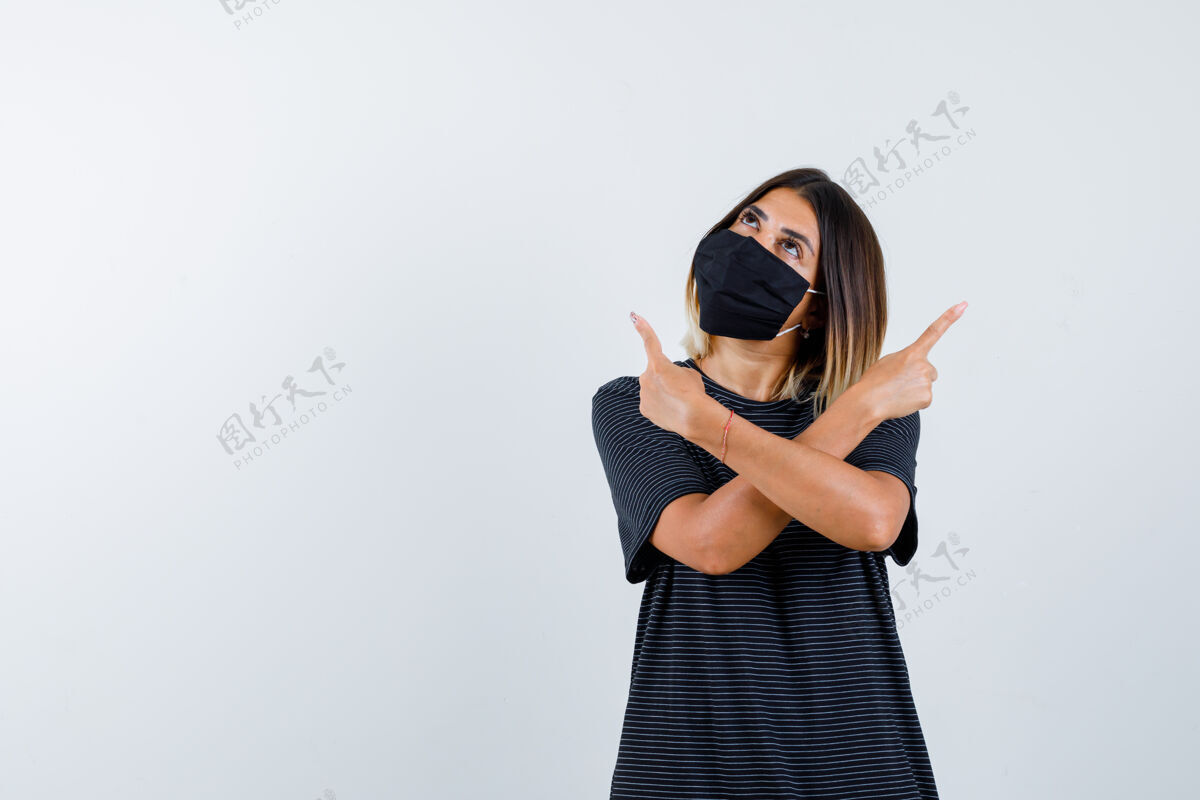 时尚一个穿着黑色衣服 戴着黑色面具的年轻女子 用食指指向相反的方向 向上看 沉思着 俯视前方黑发微笑目录