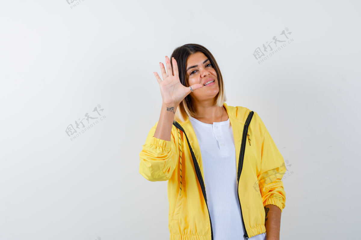 护理身穿白色t恤 黄色夹克的年轻女孩 显示停车标志 看上去很欢快 正面视图娱乐时尚喜悦
