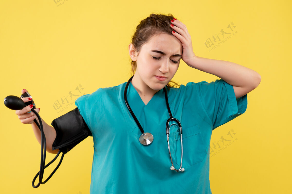 健康前视图穿着医用衬衫的女医生正在检查她的压力 病毒健康情绪 covid-19大流行制服人黄色听诊器