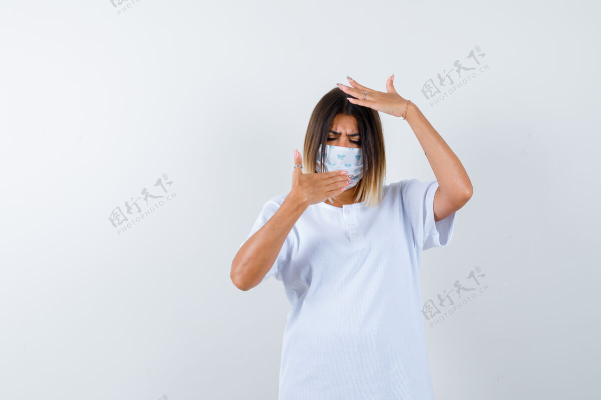 皮肤穿着t恤的年轻女性 戴着口罩手捂嘴 手捂头 神情犹豫不决 前视健康亚洲人女人