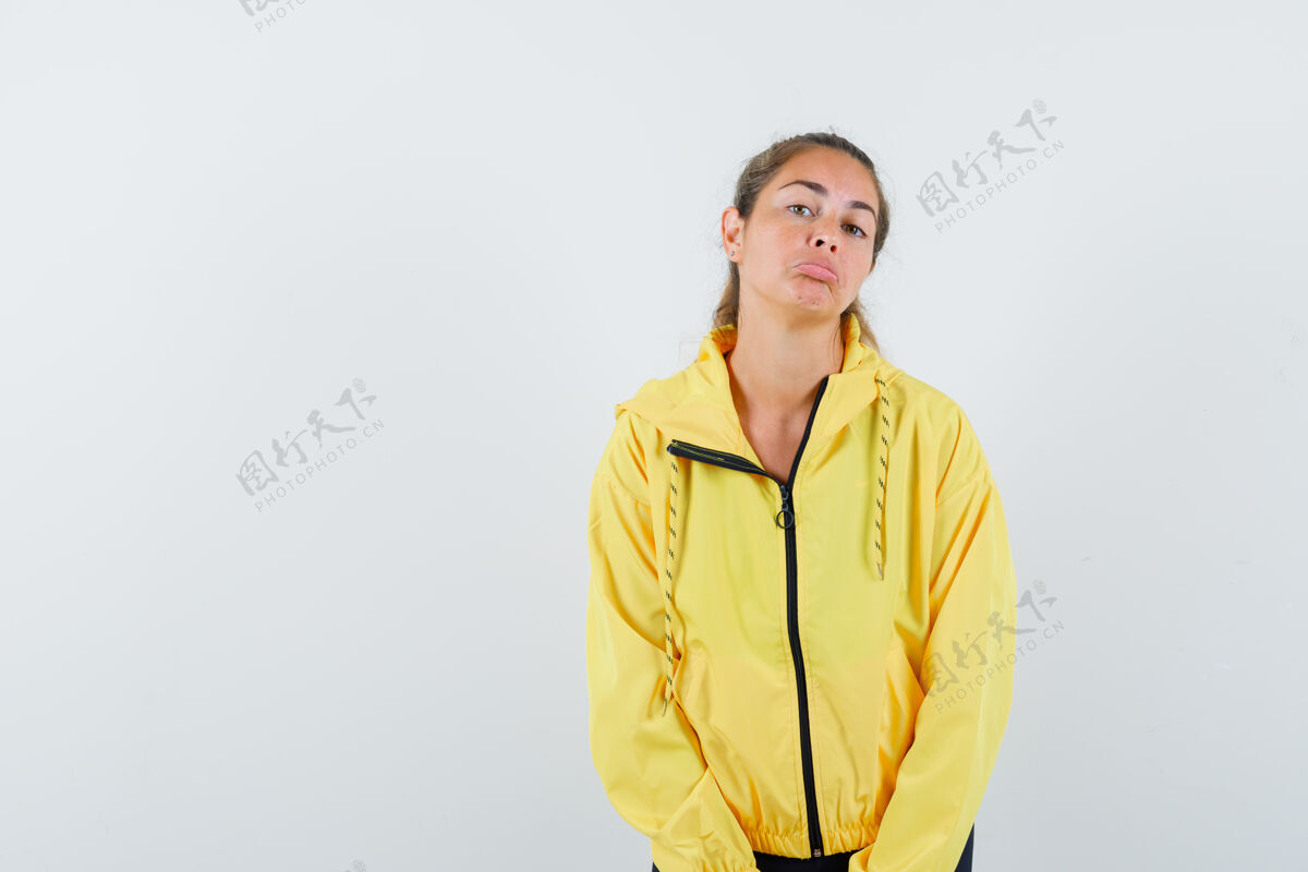 模特年轻女子站直了 穿着黄色棒球服和黑色裤子摆在前面 看起来很严肃自然成人夹克