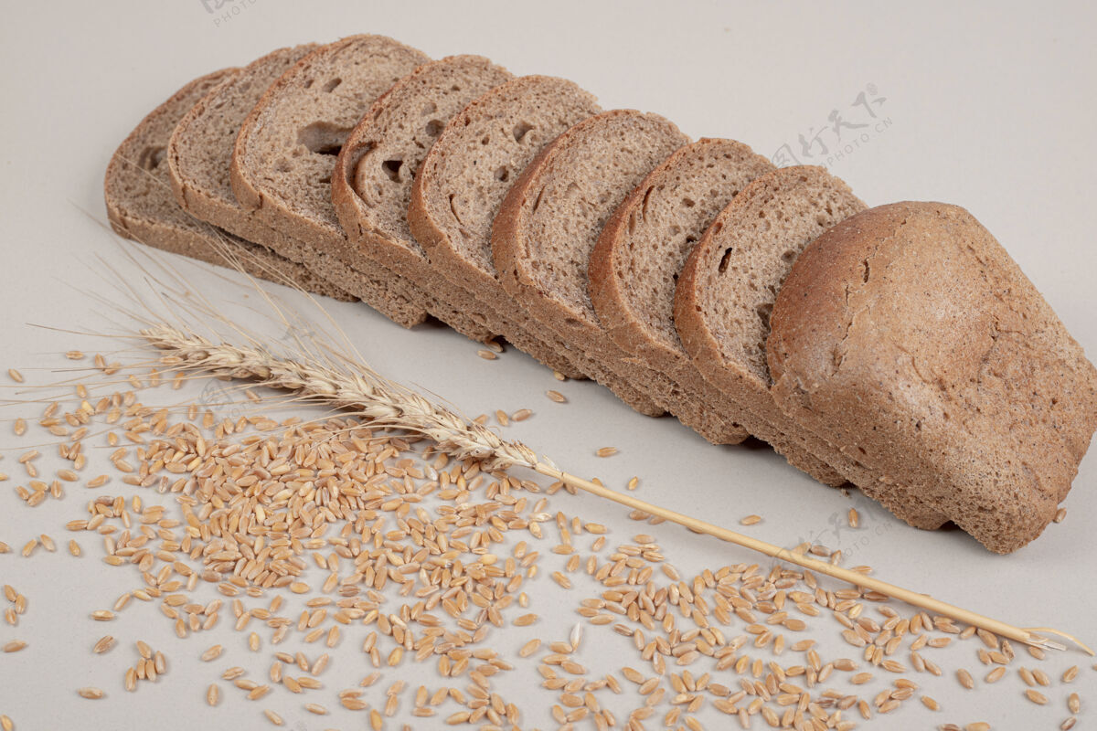烘焙切片新鲜的棕色面包 白色表面有燕麦粒美味营养脆