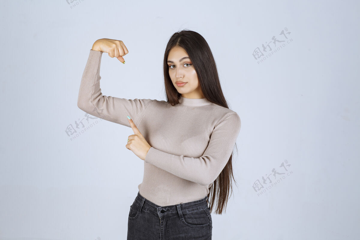 服装穿灰色毛衣的女孩展示她的拳头和力量人体模特员工聪明