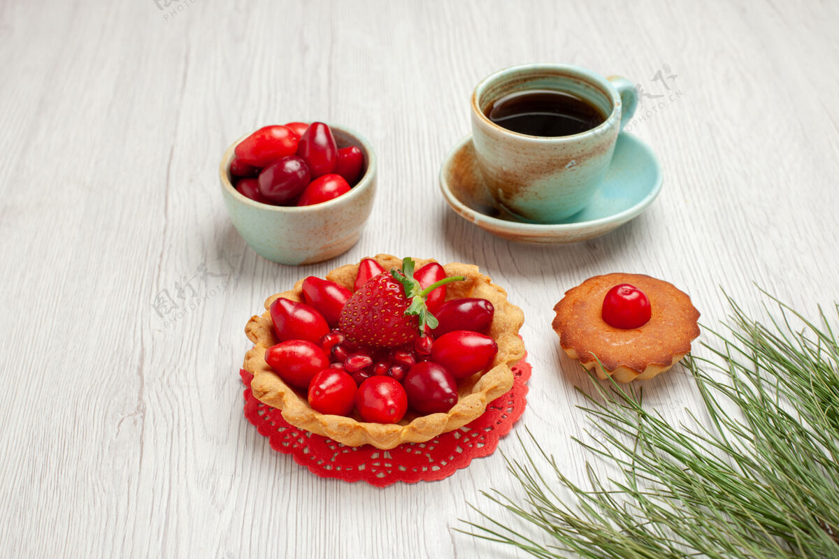 草莓前视小蛋糕上有水果和一杯茶 白色桌面上有水果甜点彩茶杯子水果盘子