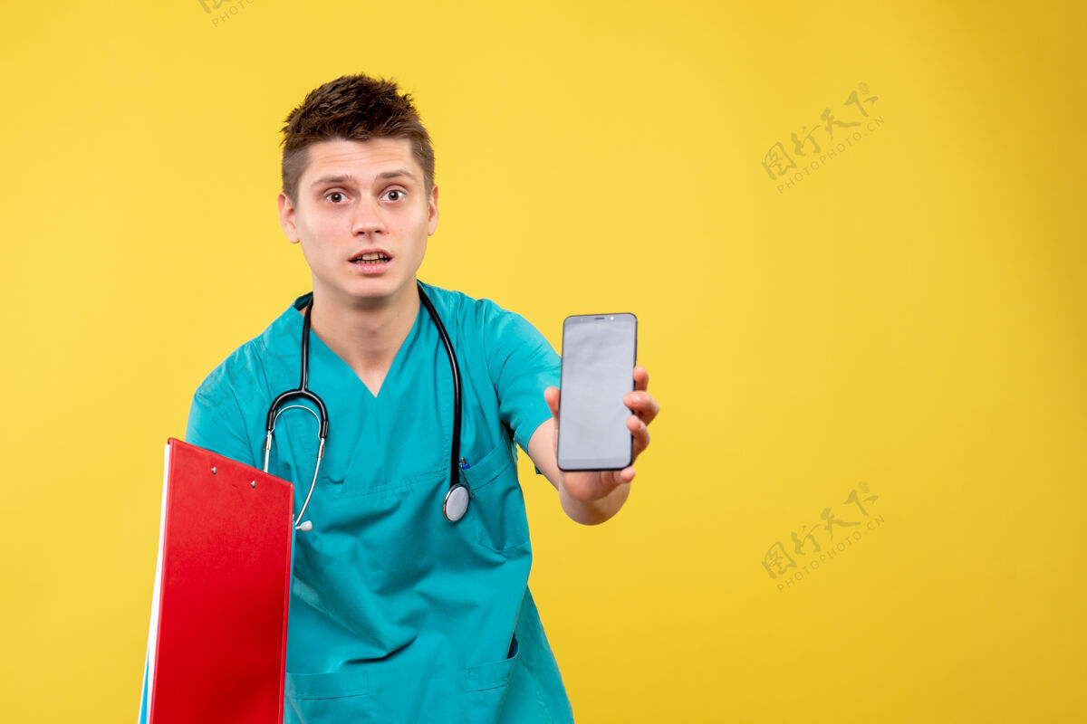 电话身穿医疗服的男医生正面图 黄色墙上有电话和便条病毒健康正面