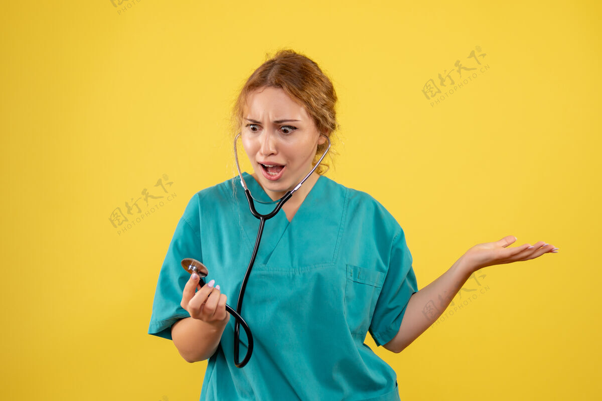 护士黄色墙上穿着带听诊器的医疗服的女医生的正视图西装女医生健康