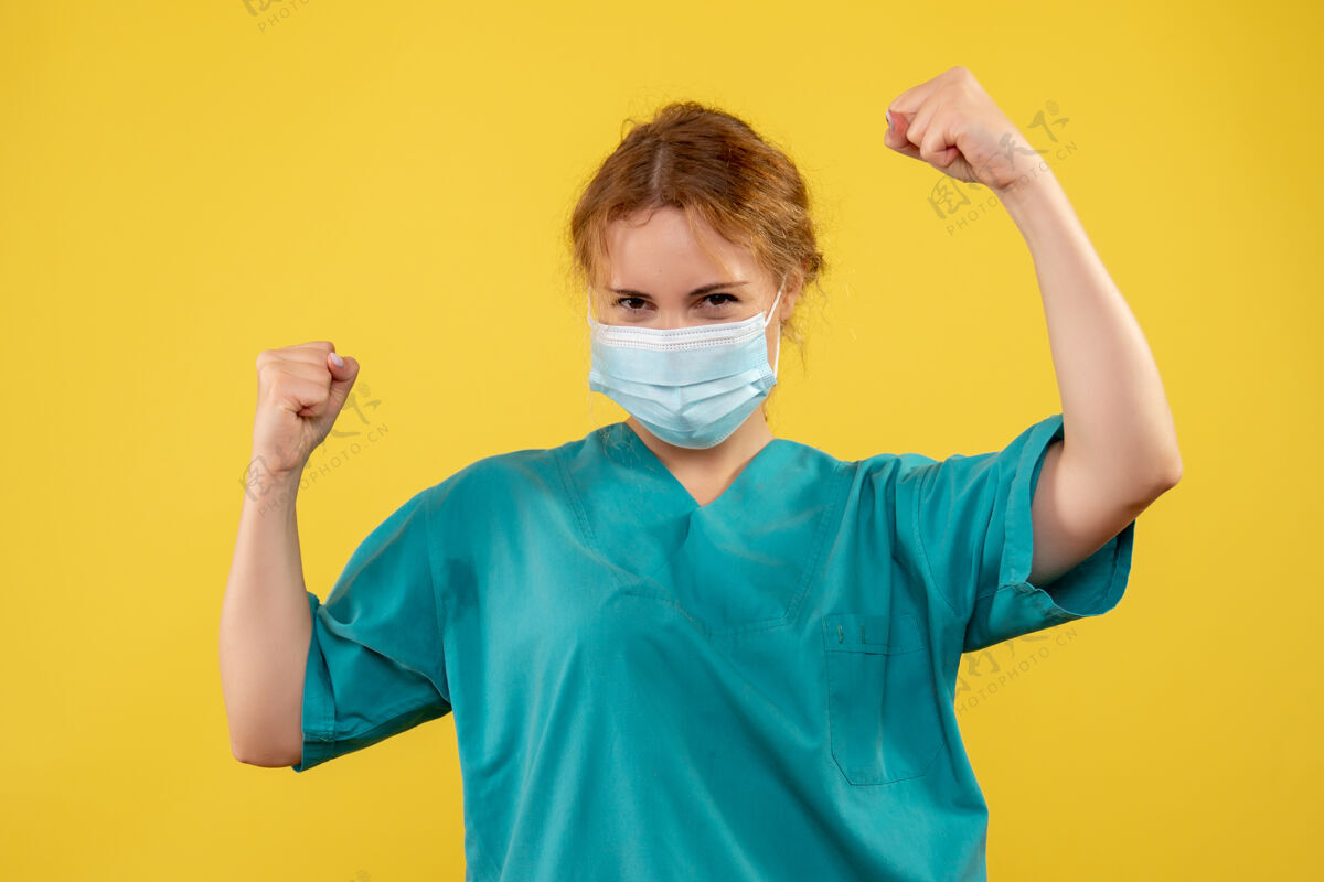 男性身着医疗服 戴着口罩的女医生在黄墙上欢呼雀跃的正面图医院家庭主妇成人