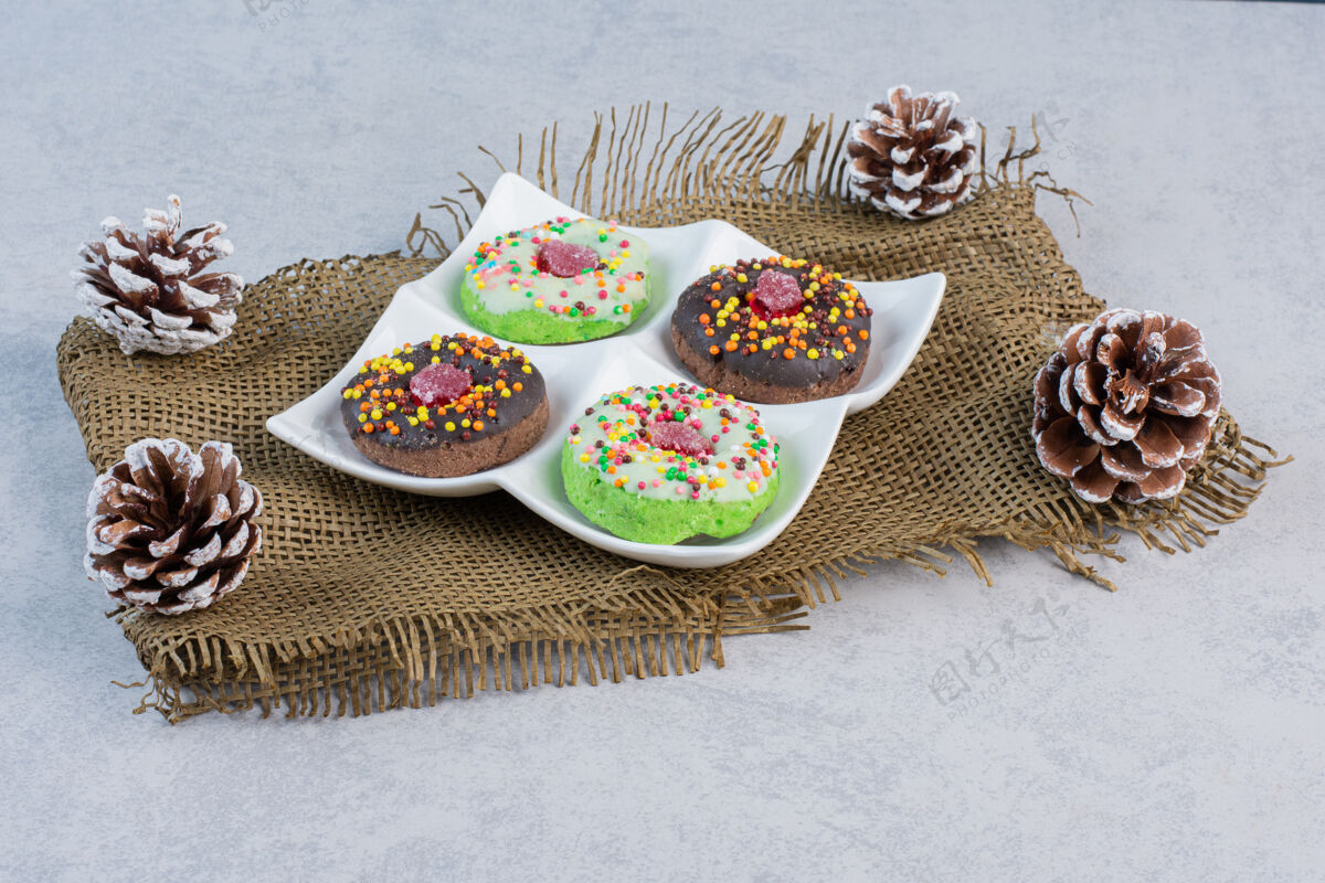 松树在大理石桌上的一块布上放着松果中的一盘甜甜圈糕点甜点巧克力