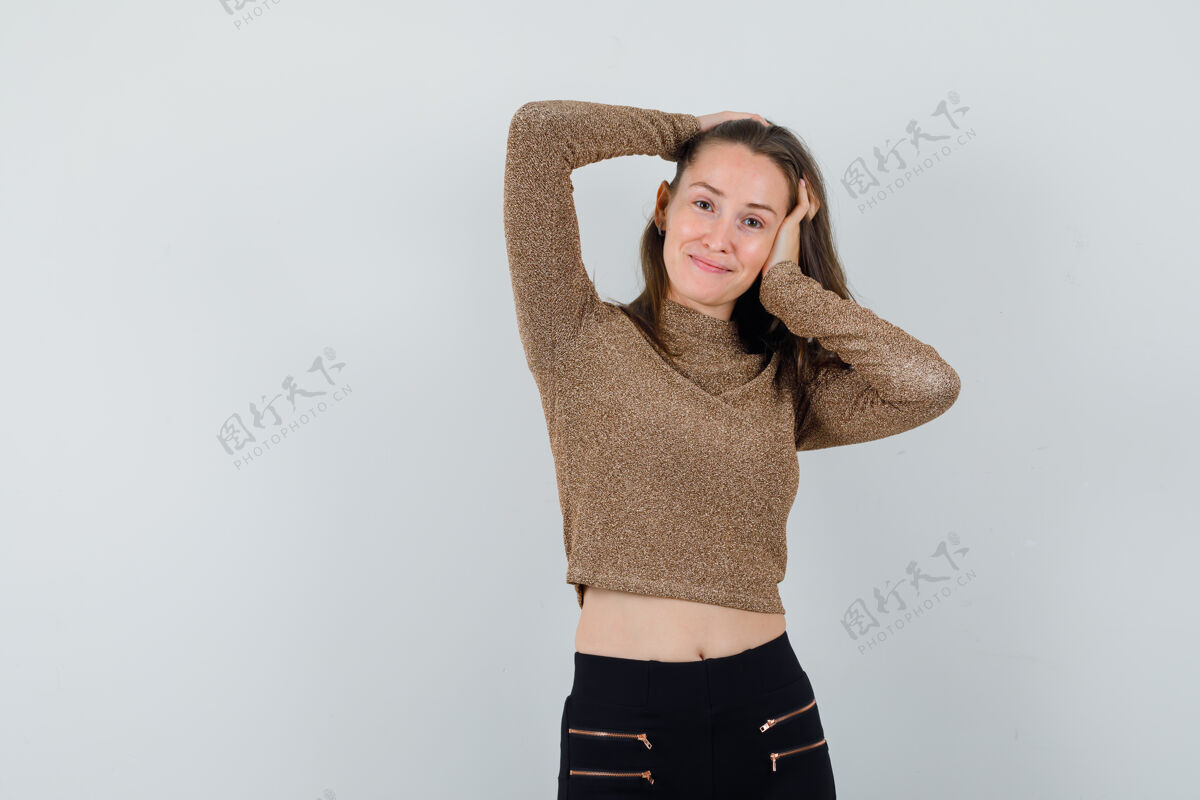水疗一个年轻的女人 手举着头 穿着金色的毛衣和黑色的裤子 看起来很开心新鲜护理年轻