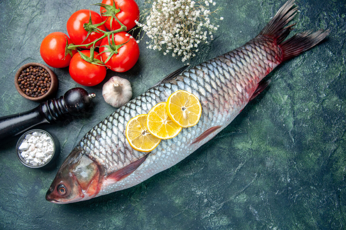 刀顶视图新鲜的生鱼肉与西红柿和柠檬在深蓝色的背景柠檬肉水平