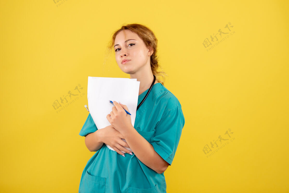 持有黄墙上穿着医疗服的女医生手持分析图医疗微笑健康