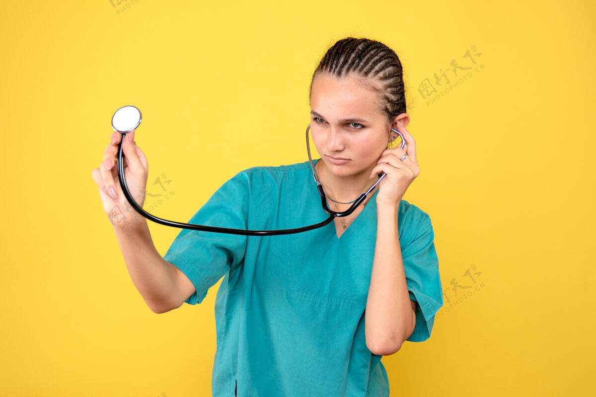 听诊器黄色墙上穿着带听诊器的医用衬衫的女医生的正视图情绪仪器健康