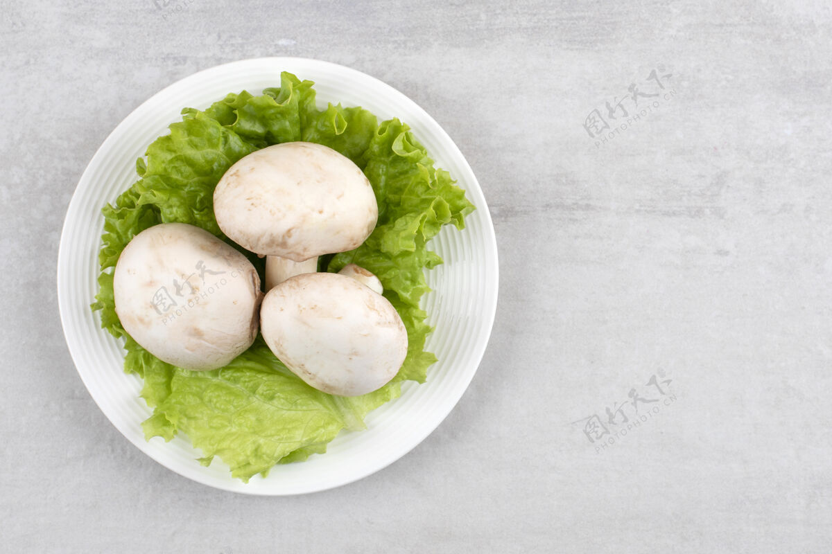 蔬菜石桌上摆着一盘白蘑菇和生菜生的健康美食