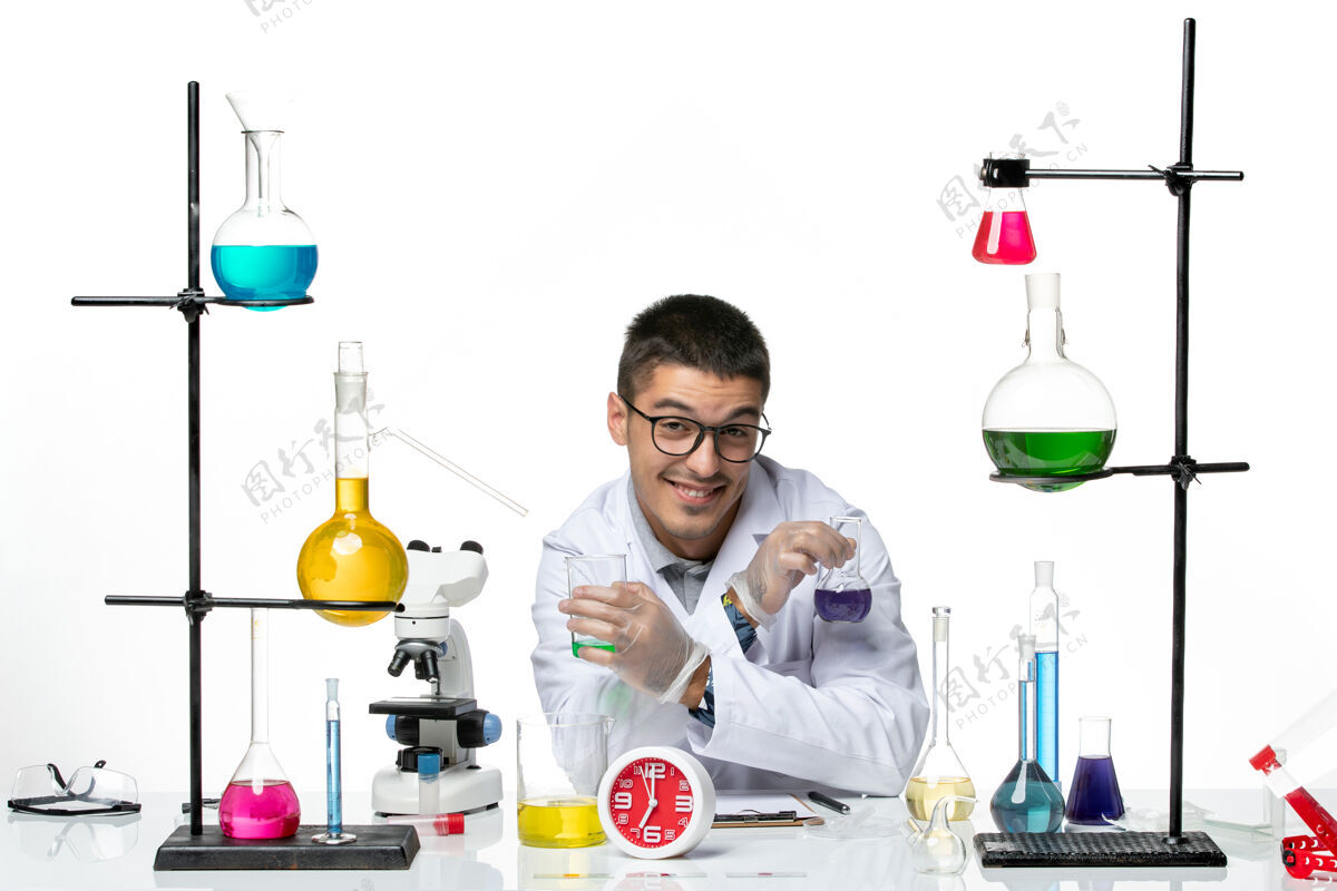 玻璃正面图：身穿白色医疗服的男性化学家拿着装有溶液的烧瓶 在白色背景上微笑着病毒科学冠状病毒-大流行实验室套装实验室烧杯