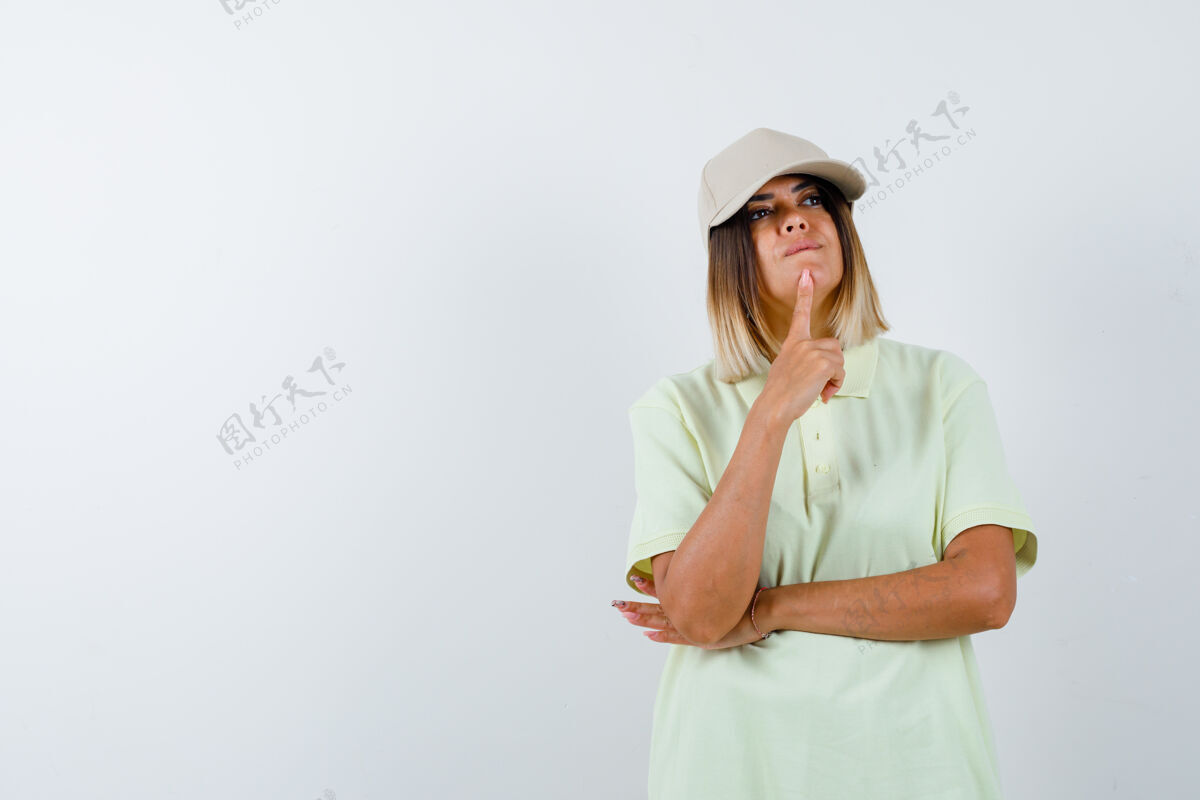 亚洲年轻女士穿着t恤 戴着帽子 站在思考的姿势 看着深思熟虑的前景色前面人自然