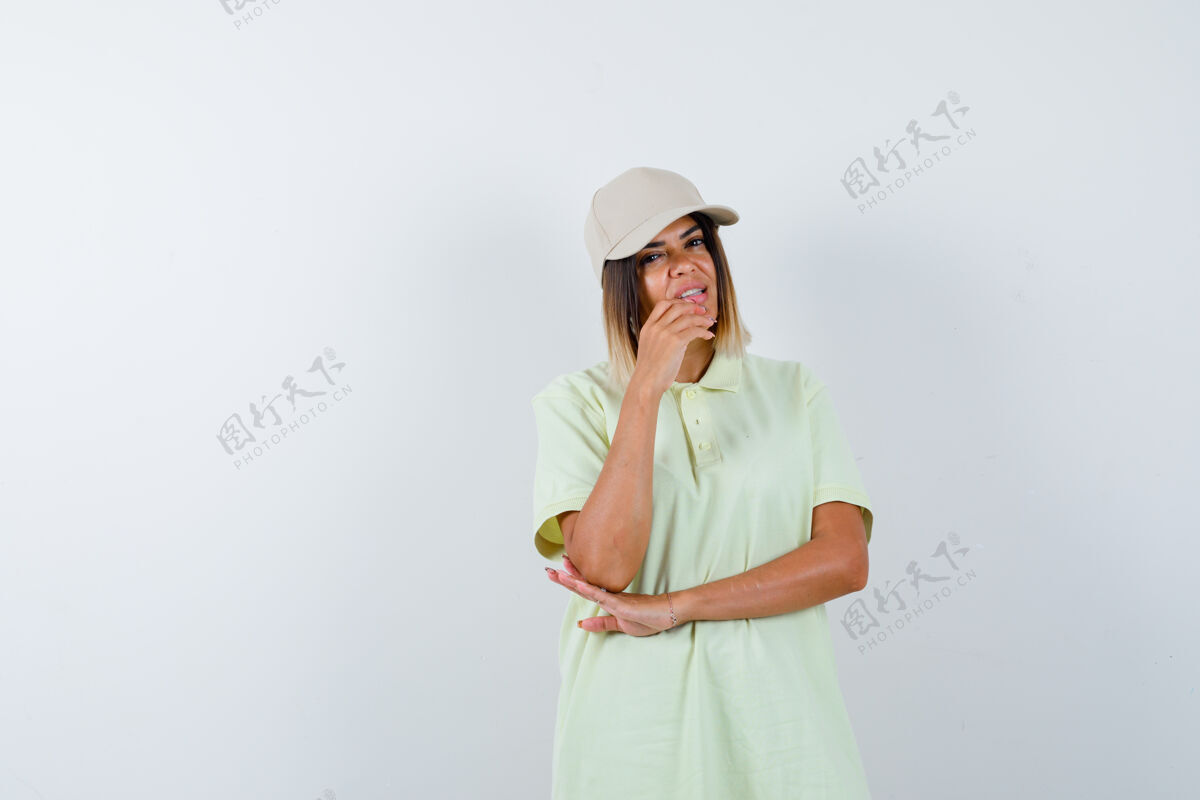 微笑穿着t恤 戴着帽子的年轻女士站在思考的姿势 看起来沉思 前视图完美黑发护理