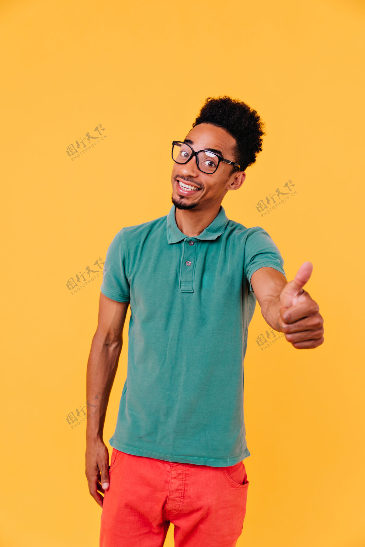 美国帅哥站着 脸上洋溢着喜悦的表情室内拍摄的是戴着大眼镜的快乐的黑发非洲男人男孩活动快乐