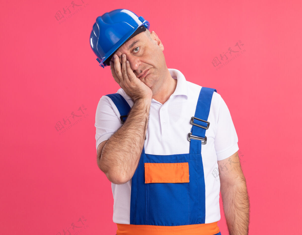 手可悲的成年白人建筑工人穿制服把手放在脸上粉红色制服建设者成年人