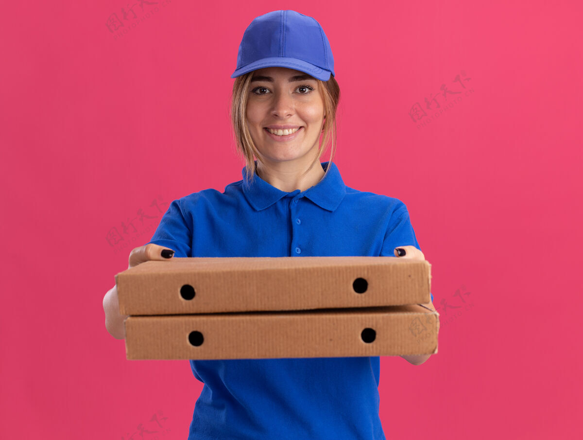 盒子微笑着的年轻漂亮的送货女孩 穿着制服 手里拿着粉红色的披萨盒送货漂亮披萨