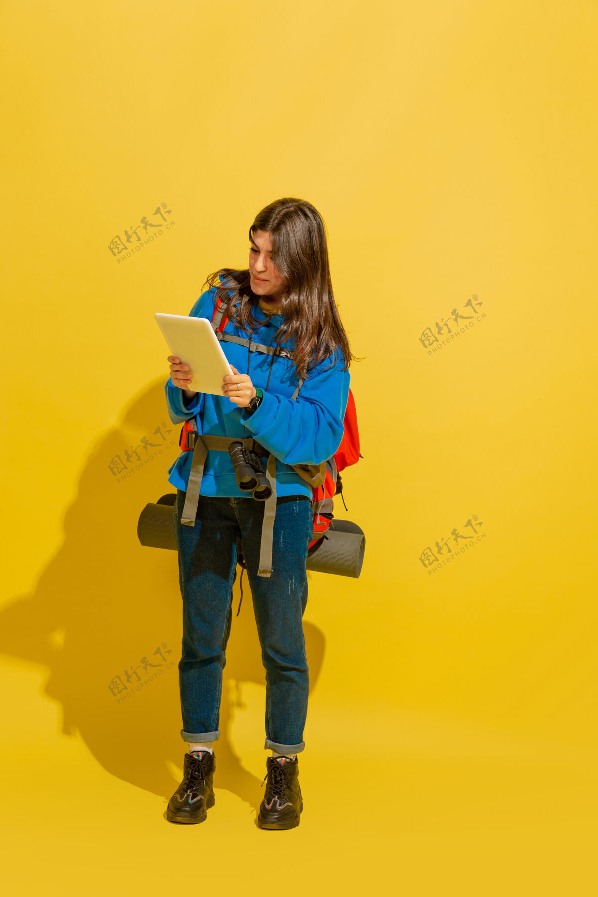 女人一个快乐的年轻白人旅游女孩的肖像 带着包和望远镜 隔离在黄色的工作室背景上人物旅行情感