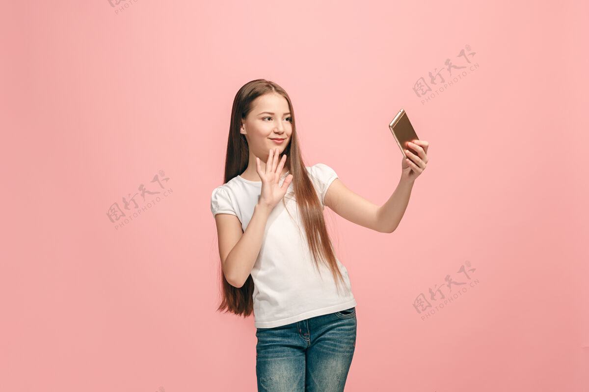 女孩快乐的少女站着 在粉色的画室背景上微笑着 人成人健康