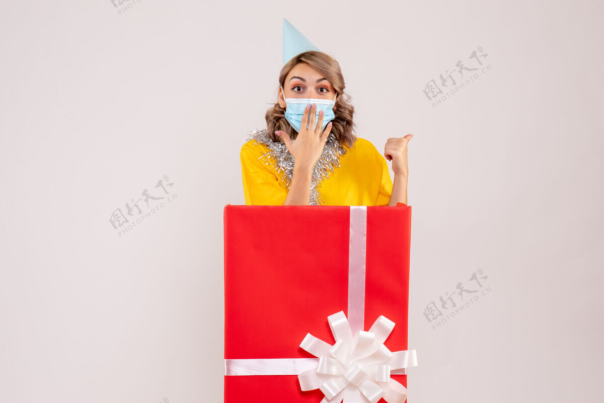圣诞节正面图：戴着面具的红色礼品盒里的年轻女性购物者购物面具