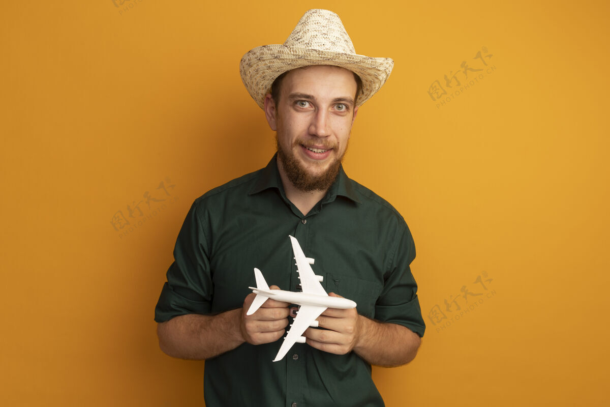 海滩笑容可掬的金发帅哥 头戴沙滩帽 手里拿着橙色的飞机模型姿势帽子黑发