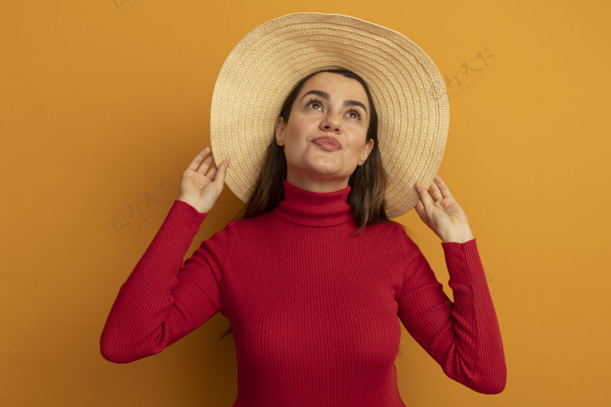 漂亮戴着沙滩帽的漂亮白种女人高兴地抬头看橙色拜托时尚帽子