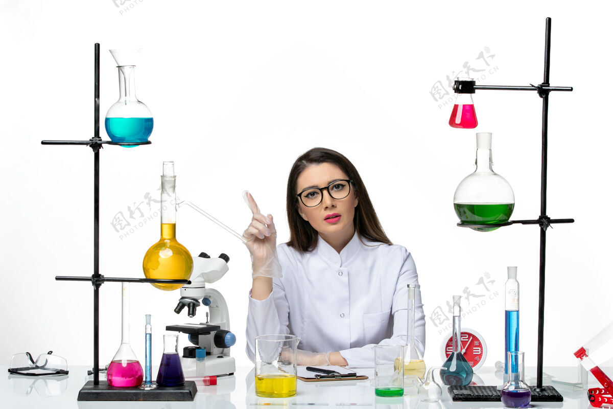 前面前视图穿着白色医疗服的女化学家正坐在白色背景的解决方案上-科学大流行实验室病毒坐着药品瓶子
