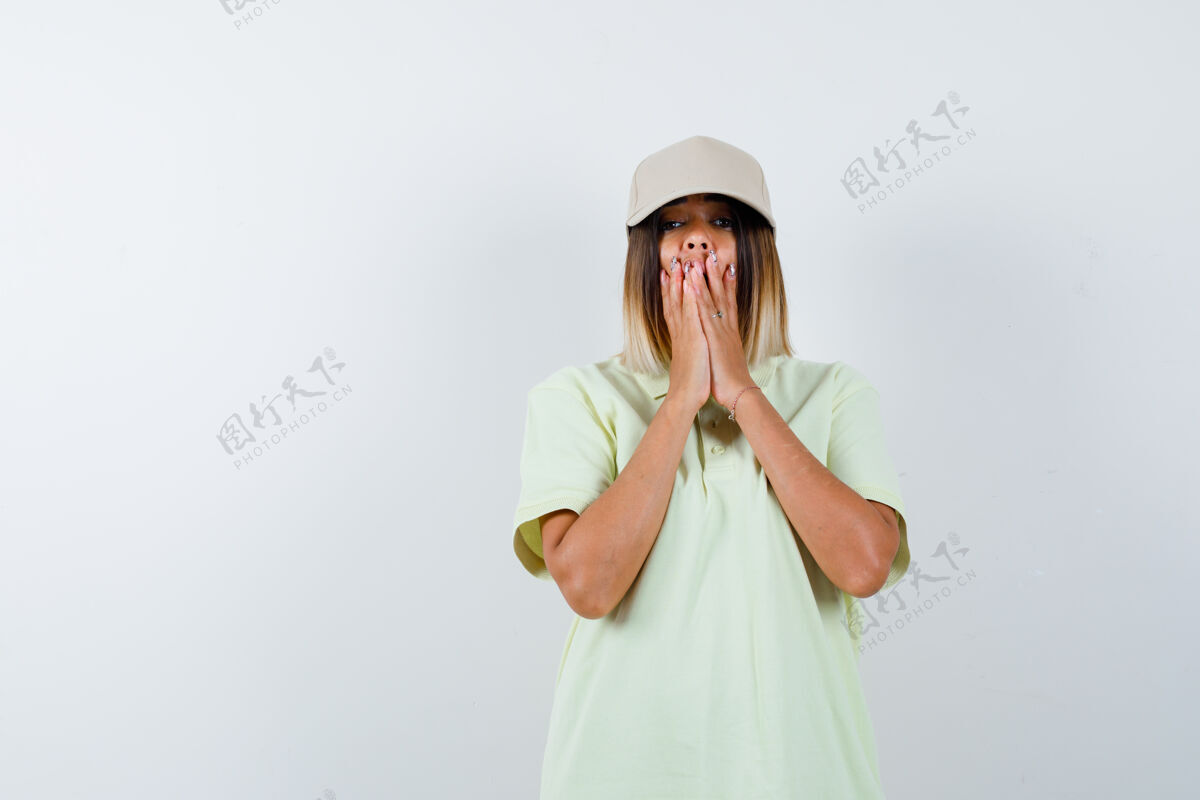 健康年轻的女士手放在t恤衫上 戴着帽子 神情迷惑不解 俯视前方模型亚洲女士