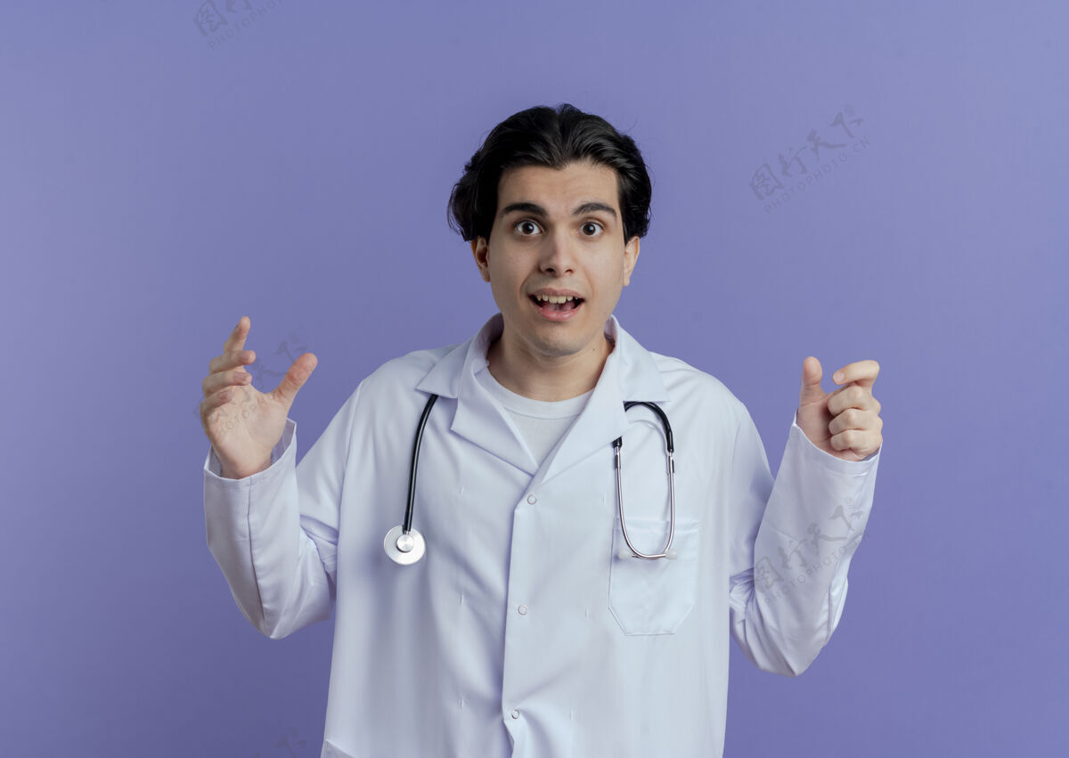 手令人印象深刻的年轻男医生穿着医用长袍和听诊器看着保持双手在空气中保持双手隔离长袍男人空气