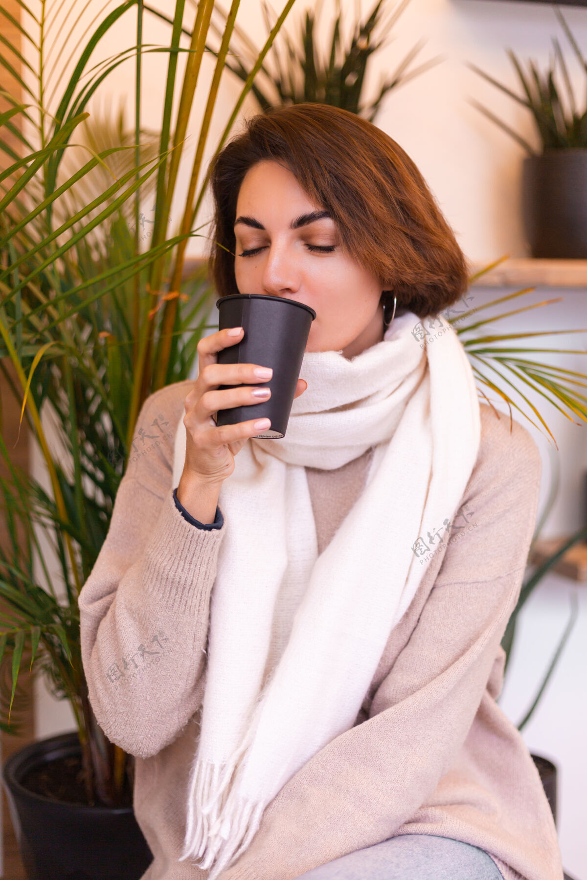 冬天一个女孩在舒适的咖啡馆里用一杯热咖啡取暖杯子脸成人