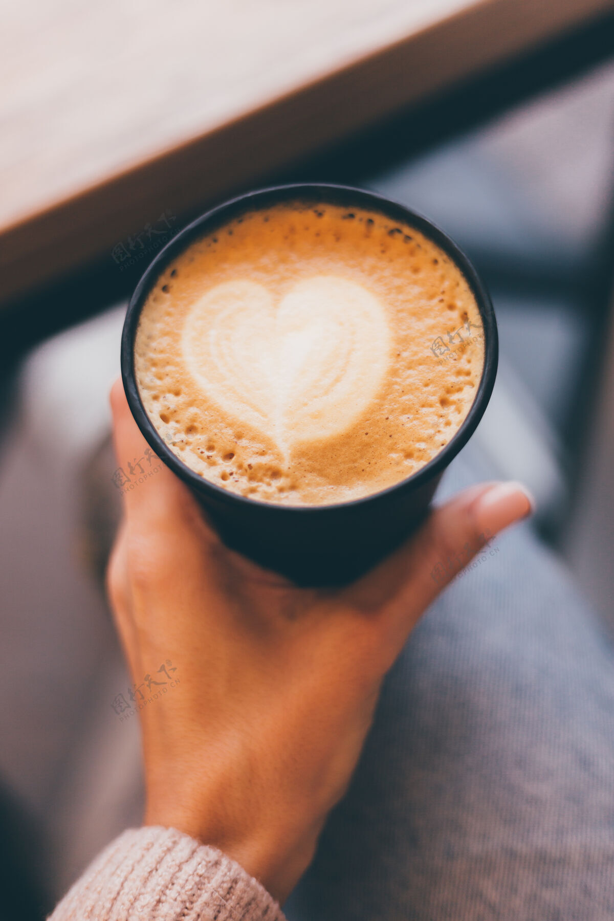 艺术镜头中的女人手拿一杯热咖啡 用泡沫做成的心形图案爱手咖啡店