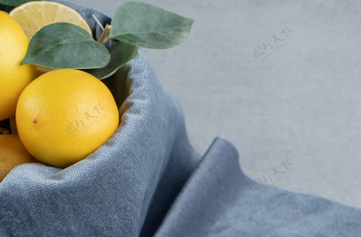 新鲜柠檬放在一个桶里 桶上覆盖着一块织物 放在大理石上饮食健康营养