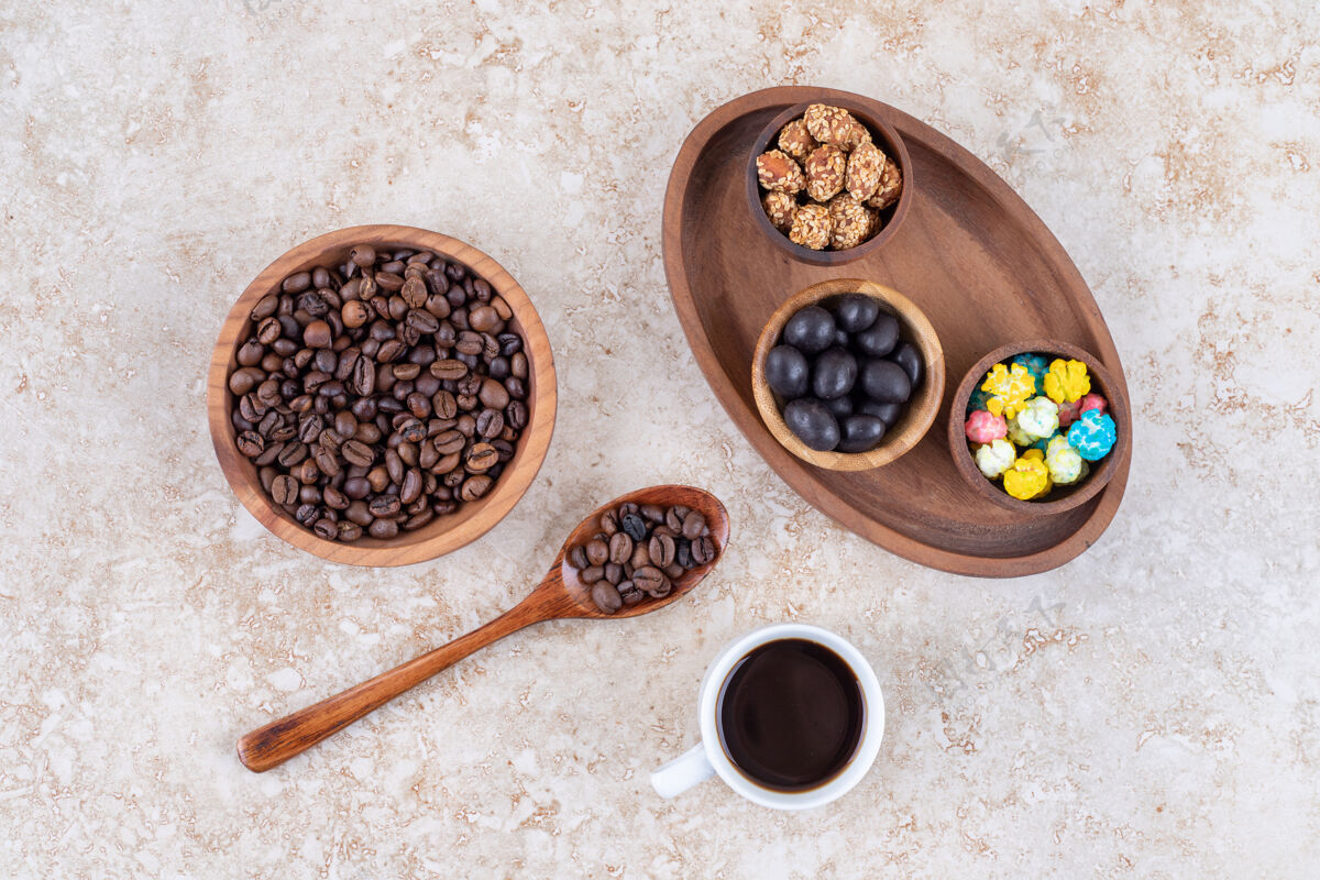 咖啡因在咖啡豆和一杯煮好的咖啡旁边的一个木制托盘里放各种小吃釉面零食杯子