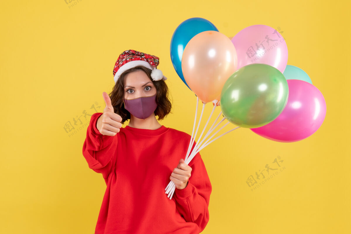 气球正面图年轻女性手持气球 戴着黄色的无菌面具乐趣情绪年轻女性