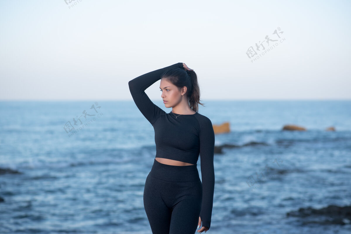 女性年轻的拉丁女性穿着黑色运动服 站在沙滩上摆姿势女士运动运动服