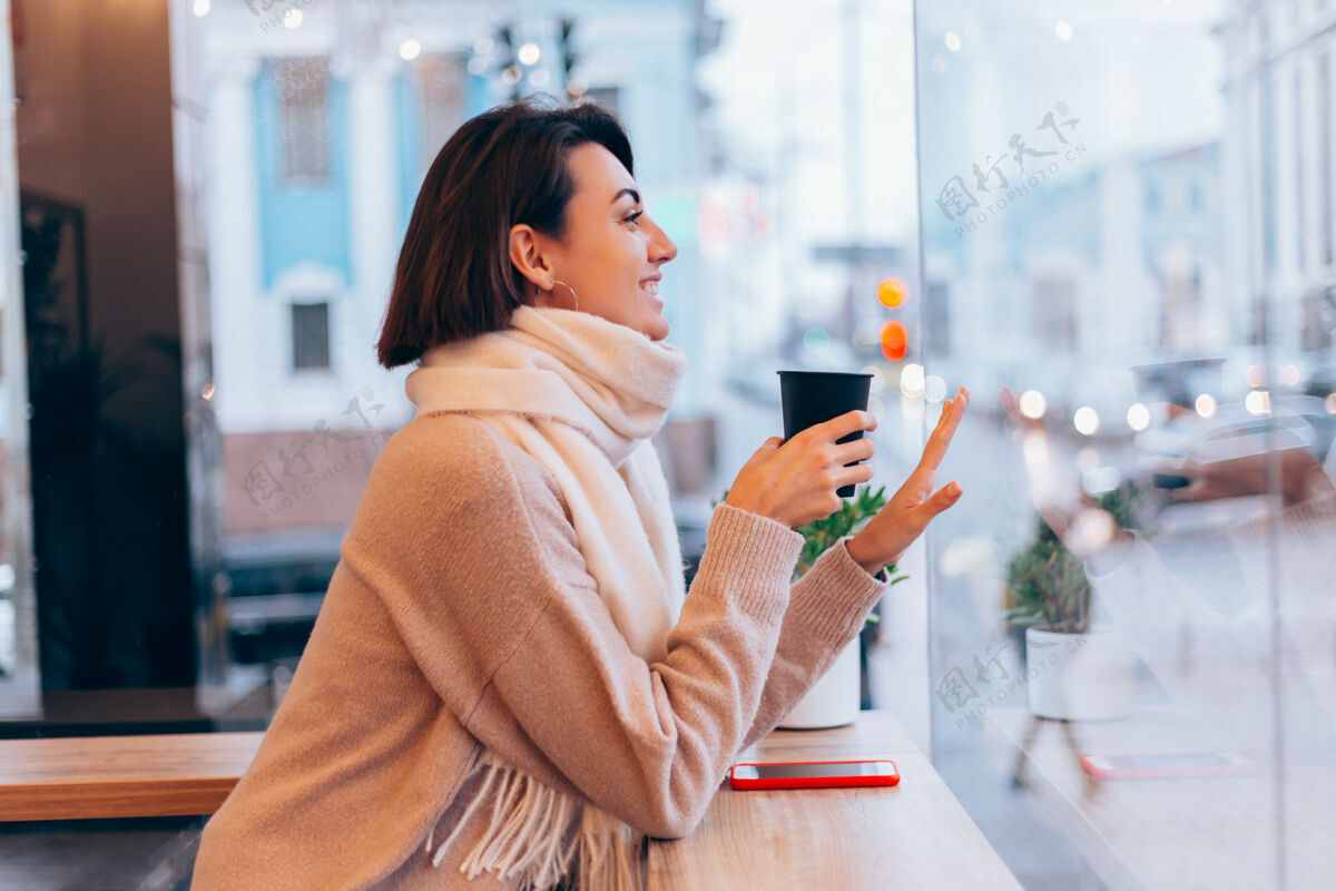 咖啡馆一个女孩在舒适的咖啡馆里用一杯热咖啡取暖坐着杯子桌子