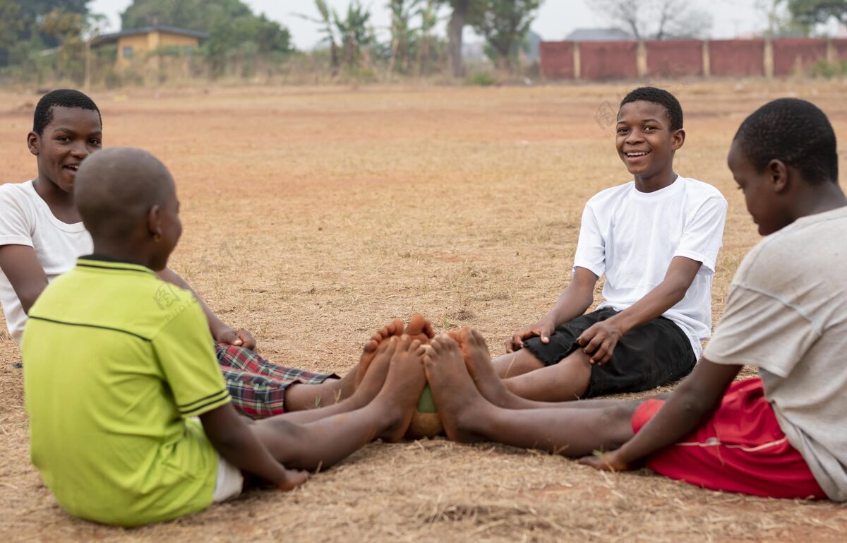 孩子坐着足球的非洲孩子们玩非洲足球