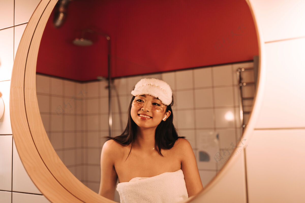 眼罩洗完澡后 黑发女人戴着毛巾 戴着睡眠面罩 欣赏着镜子里的自己化妆浴室刷子