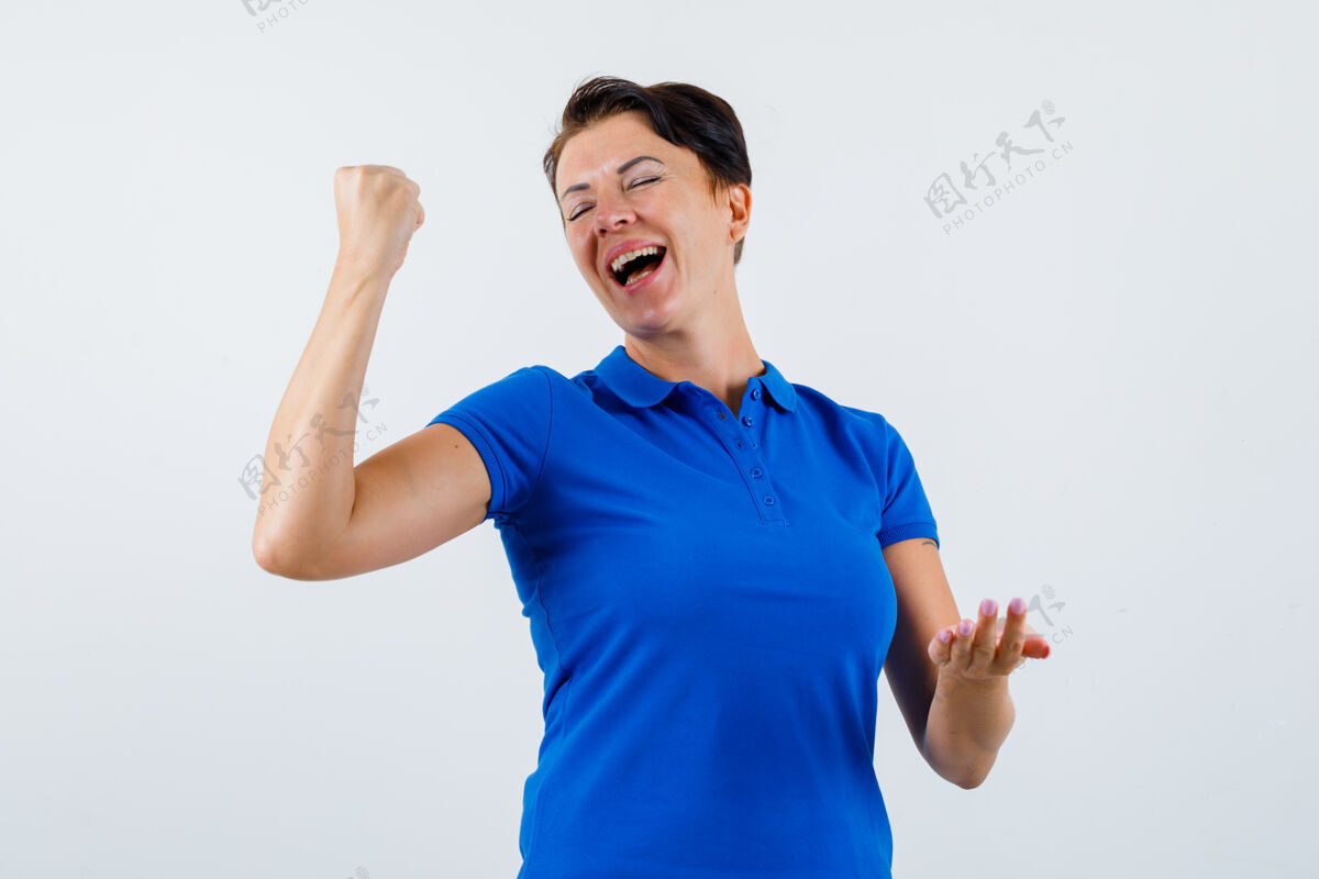 人身着蓝色t恤的成熟女性展示赢家姿态 看起来很开心正面视图自然皮肤漂亮