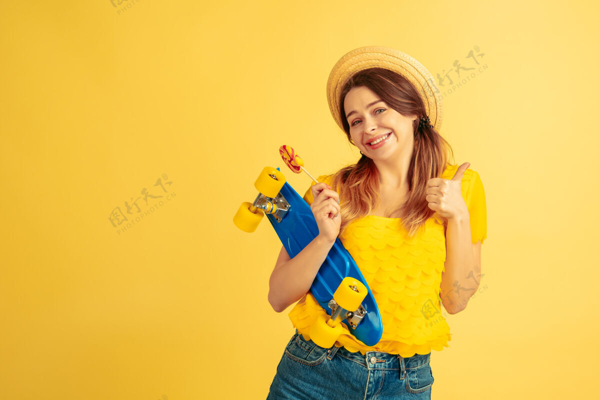 人梦幻般的 拿着溜冰鞋黄色工作室背景上的白种女人肖像戴着帽子的漂亮女模特人类情感的概念 面部表情 销售 广告夏日 旅游 度假成功人帅哥